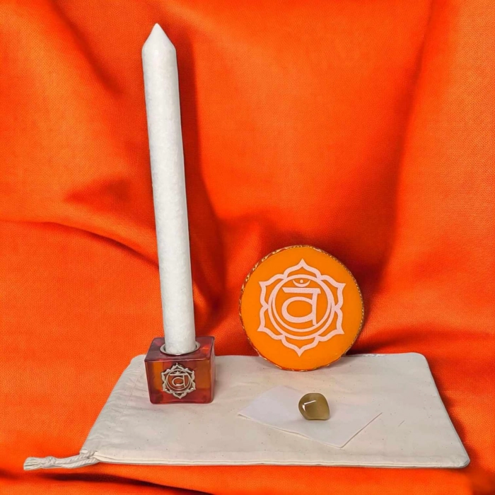 Kit rituel énergétique chakra complet avec bougie blanche, coussin rouge, pierre semi-précieuse et bougeoir racine sur fond rouge vibrant.